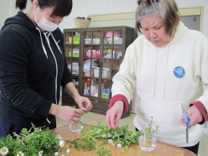 コーヒー喫茶に使うお花の準備をしている職員と利用者さん