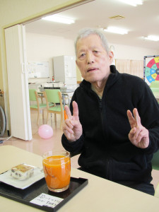 ケーキを前に笑顔でピースサインをする利用者さん