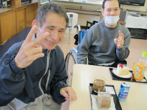 ケーキを前に笑顔でピースサインをする利用者さん